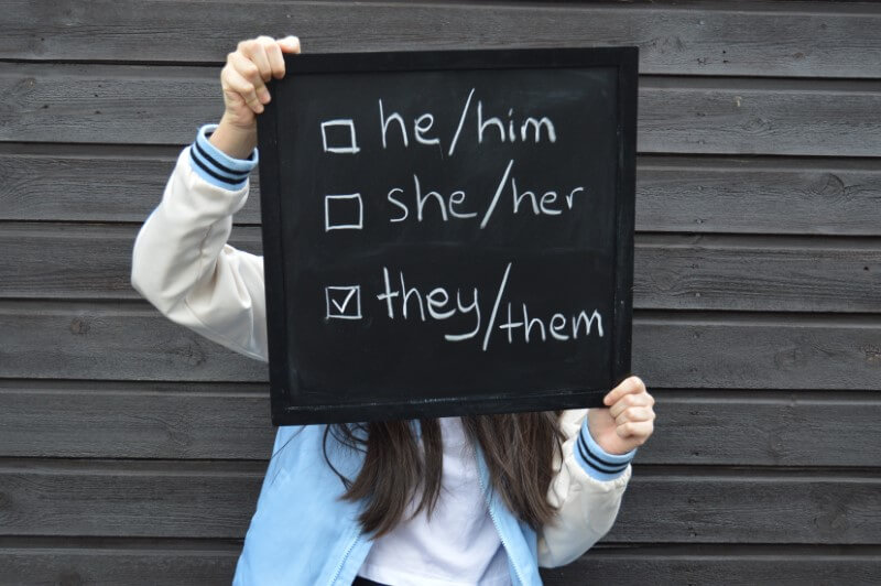 someone holding up a board with pronoun options